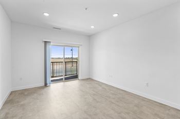 A spacious empty room with a sliding glass door leading to a balcony.